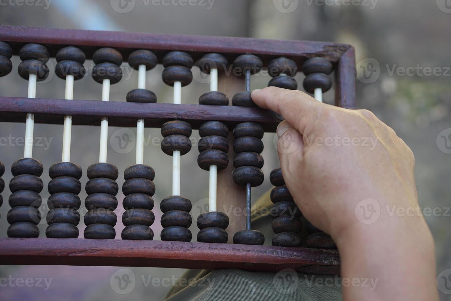 Close up man hand calculate and count wooden abacus. Concept, ancient style calculation. Counting equipment. Calculator. Educational material. Math teaching aid photo