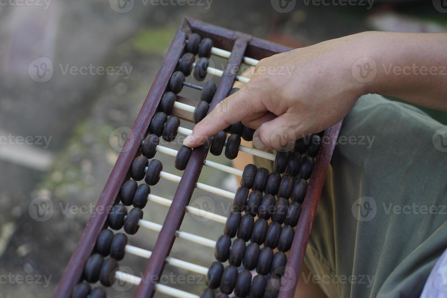 Close up man hand calculate and count wooden abacus. Concept, ancient style calculation. Counting equipment. Calculator. Educational material. Math teaching aid photo