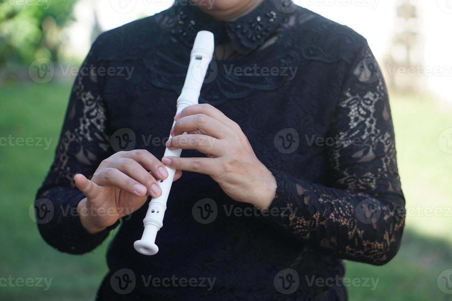 Close up woman flutist, musician is playing a recorder flute. Concept, music blowing with mouth, control with fingers on holes of flute for melody and rhythm. Mouthpiece musical instrument. photo