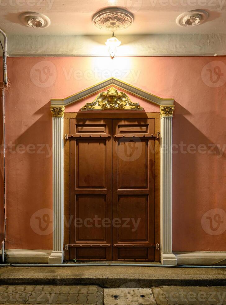 Closed wooden door of ancient portugal on pastel wall with lamp photo