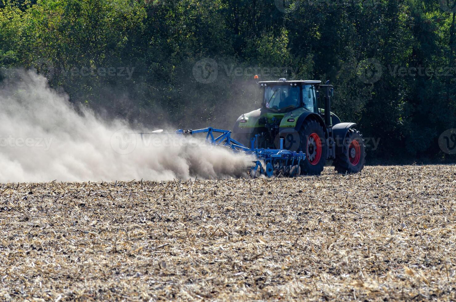 The tractor drives the field. An agricultural tractor on the cultivation of a farm field. Tractor disc harrow plows a farmer's field. Agronomy and the agricultural sector. photo