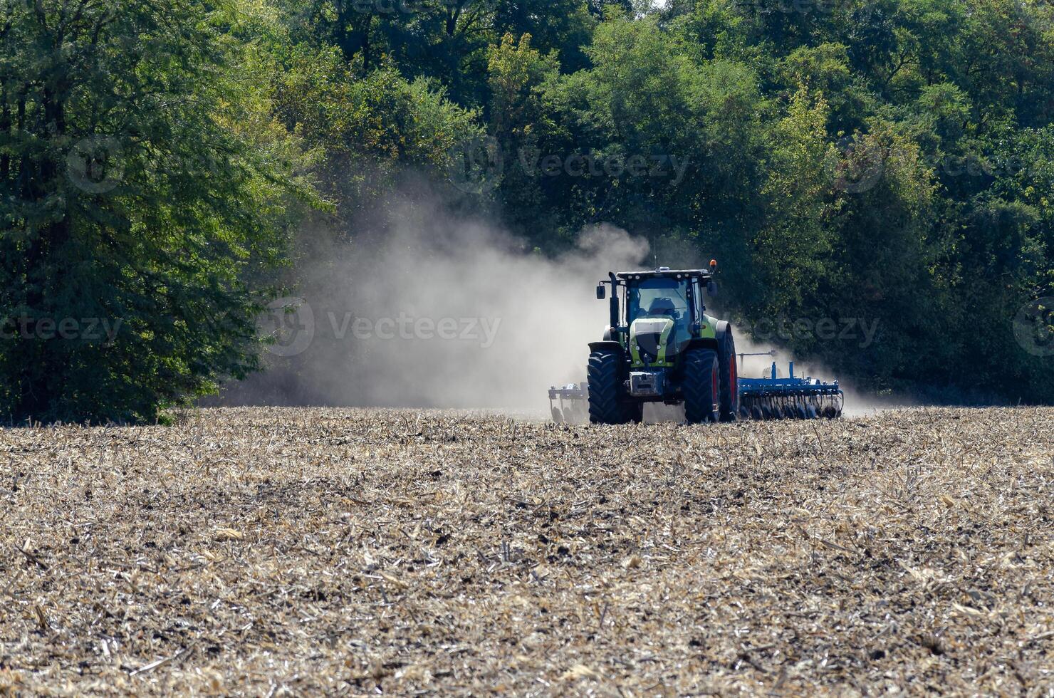 The tractor drives the field. An agricultural tractor on the cultivation of a farm field. Tractor disc harrow plows a farmer's field. Agronomy and the agricultural sector. photo
