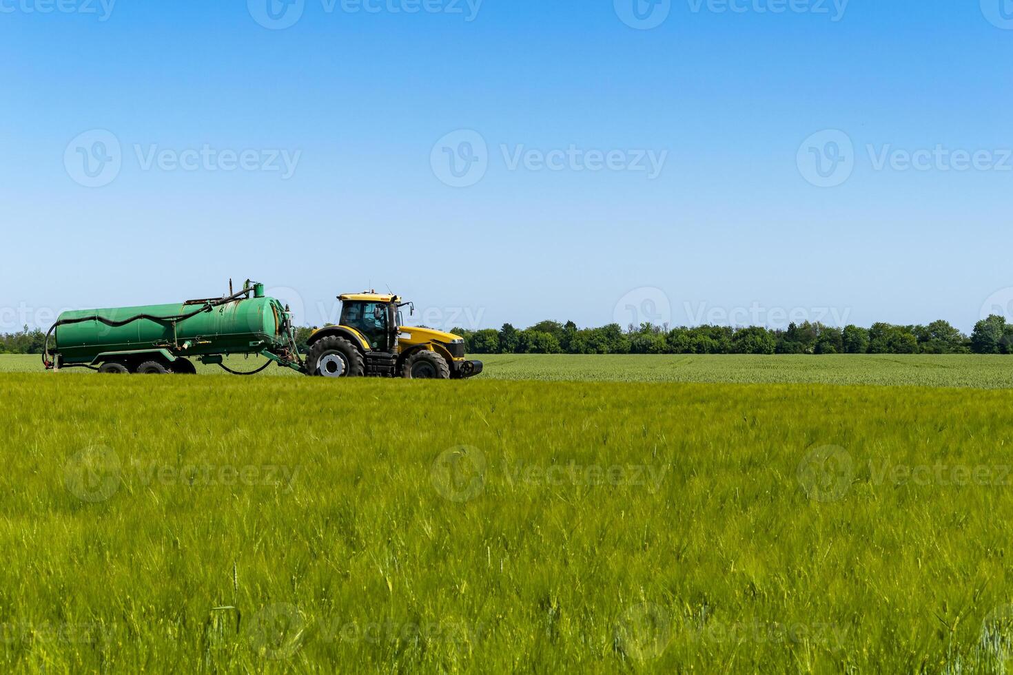 A tractor carries a barrel of liquid from pests across the field photo