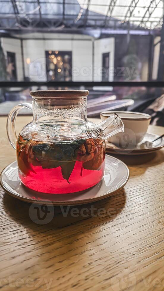 A teapot with hibiscus tea, mint leaves and walnuts. On a table in a cafe. photo