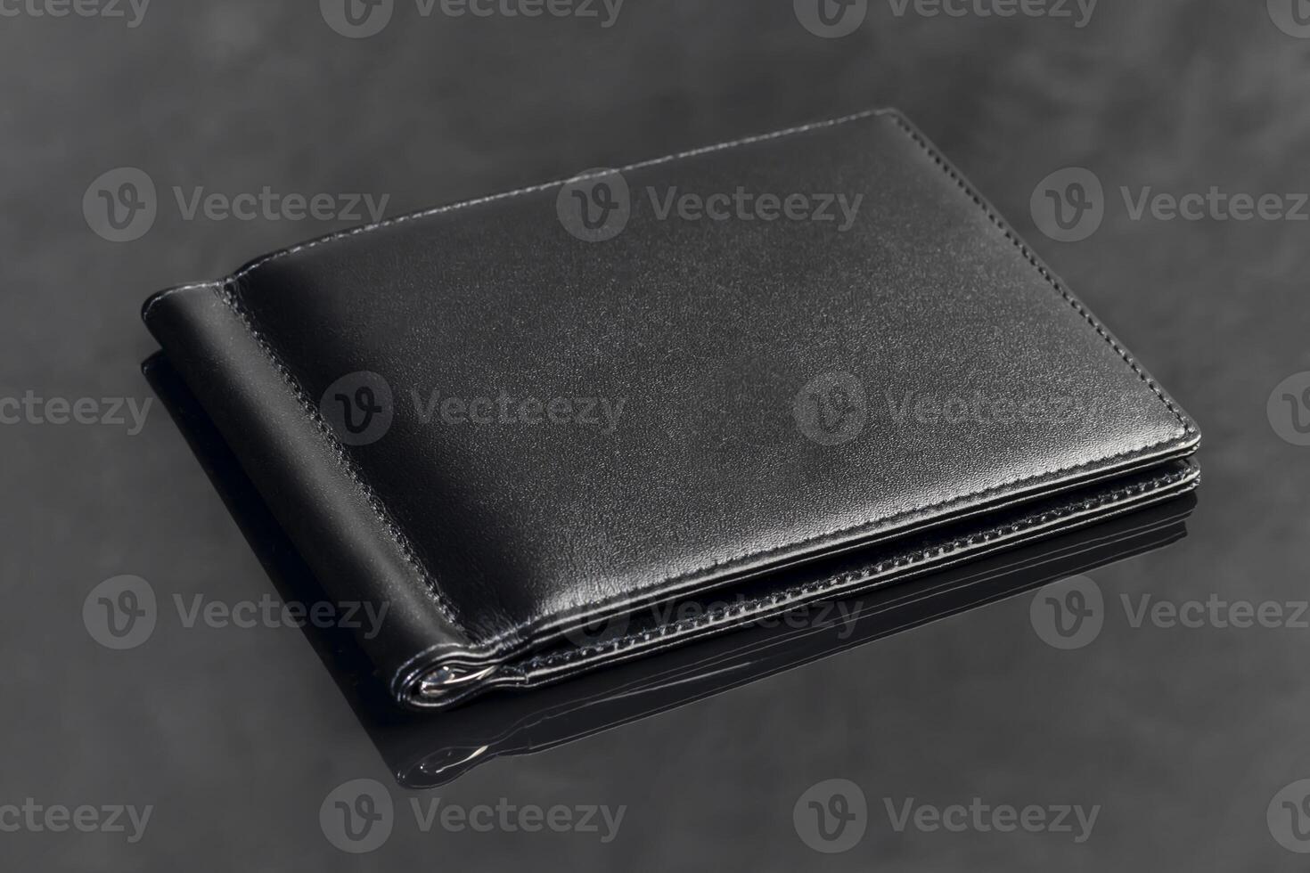 Black leather men's wallet for storing money and cards. On a dark background. photo