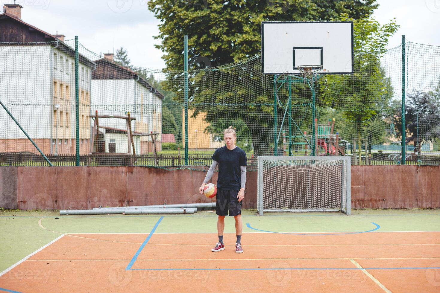 Volleyball player standing on a hard court, holding a ball with focus and determination before the game. The image captures a calm moment of preparation in an outdoor volleyball setting photo