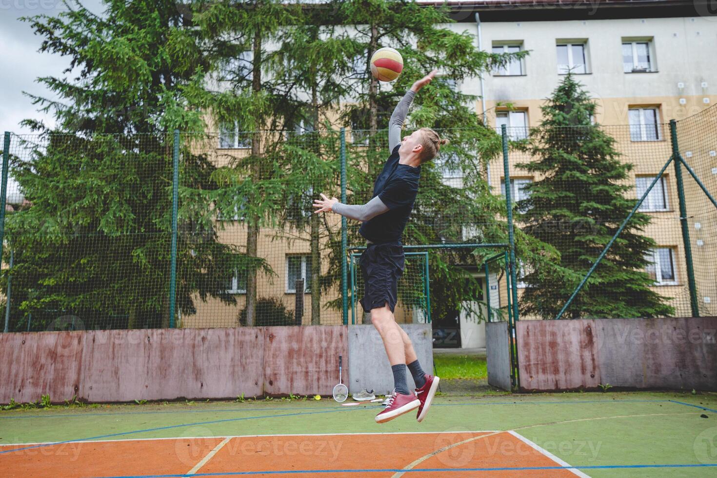 Volleyball player is serving on a hard court during an outdoor game. The action showcases athleticism, agility, and control in a dynamic volleyball setting photo