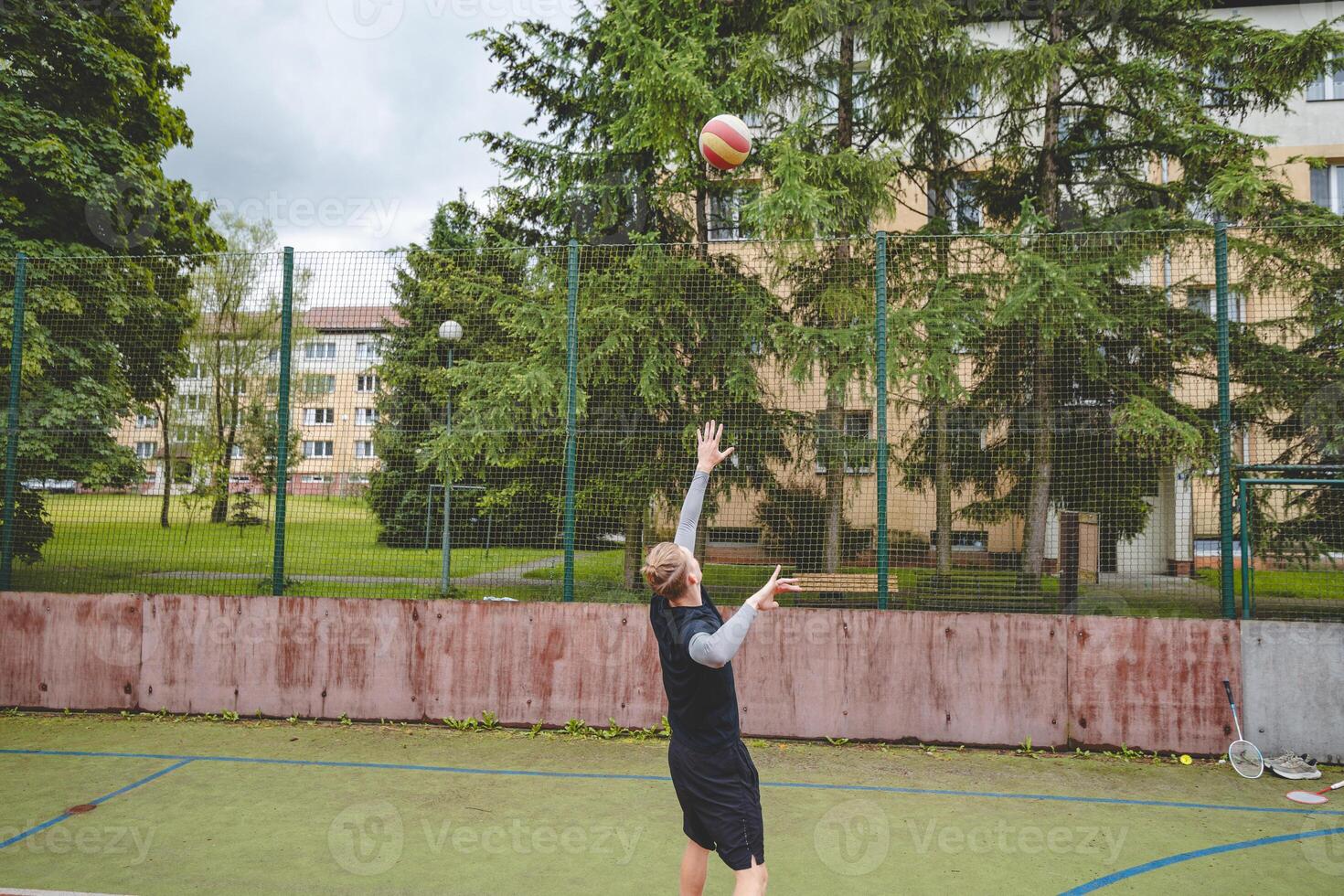Volleyball player is serving on a hard court during an outdoor game. The action showcases athleticism, agility, and control in a dynamic volleyball setting photo