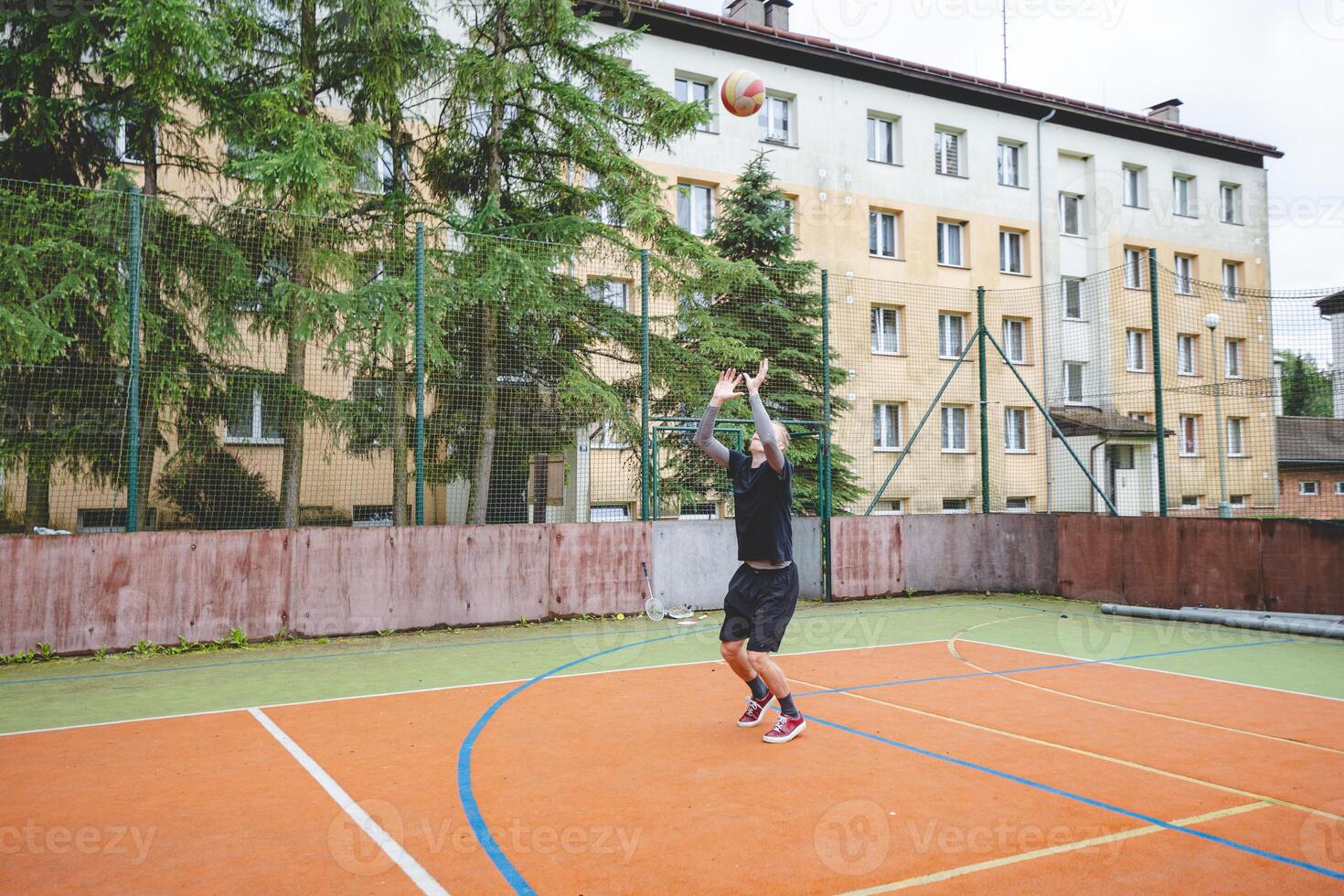 Volleyball player practicing setting the ball on a hard court, focusing on control and precision during an outdoor training session. A calm, focused moment in the game photo