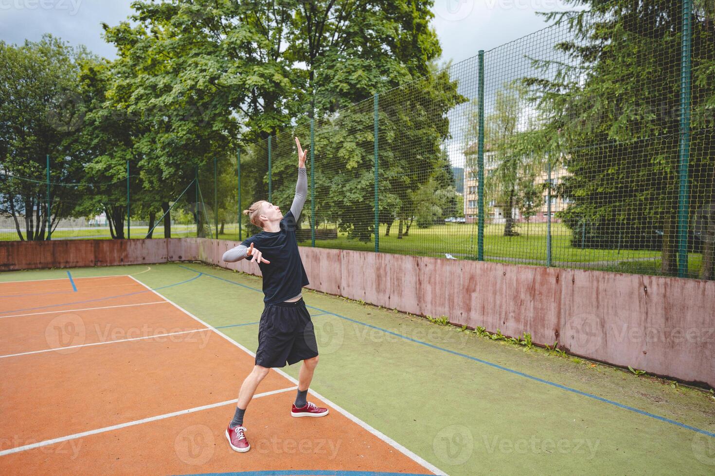 Volleyball player is serving on a hard court during an outdoor game. The action showcases athleticism, agility, and control in a dynamic volleyball setting photo