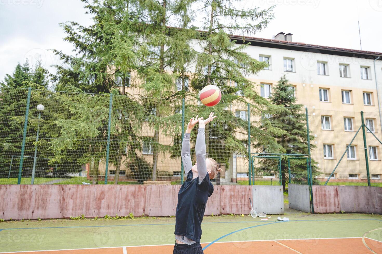 Volleyball player practicing setting the ball on a hard court, focusing on control and precision during an outdoor training session. A calm, focused moment in the game photo