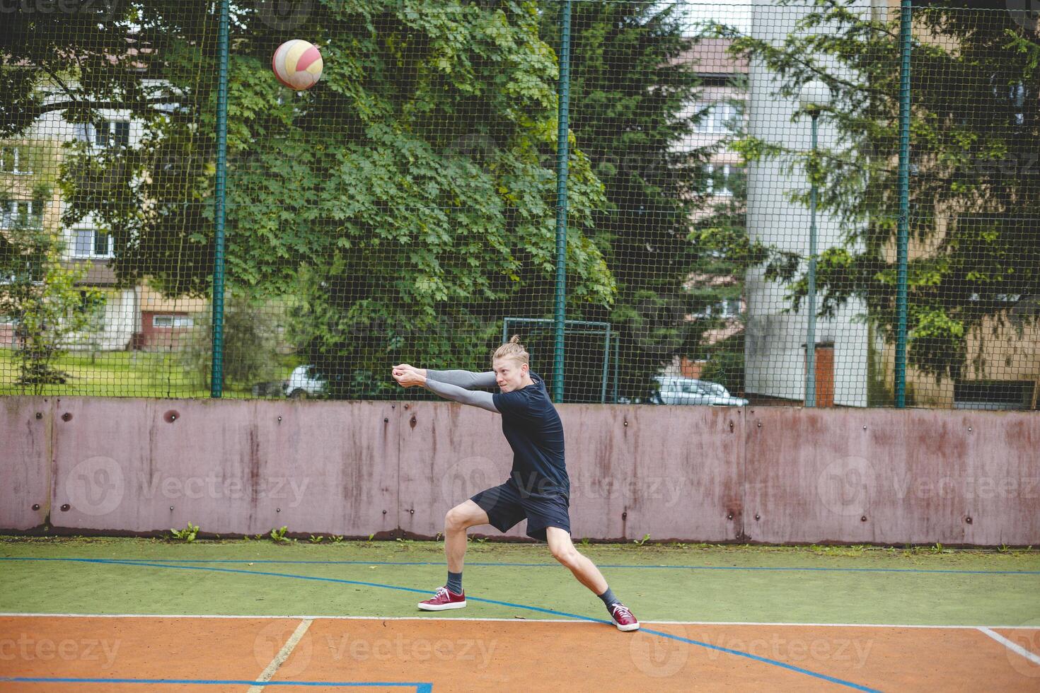 Volleyball player performing a digging on a hard court, focusing intently on the ball during an intense game. The action showcases skill, concentration, and athleticism photo