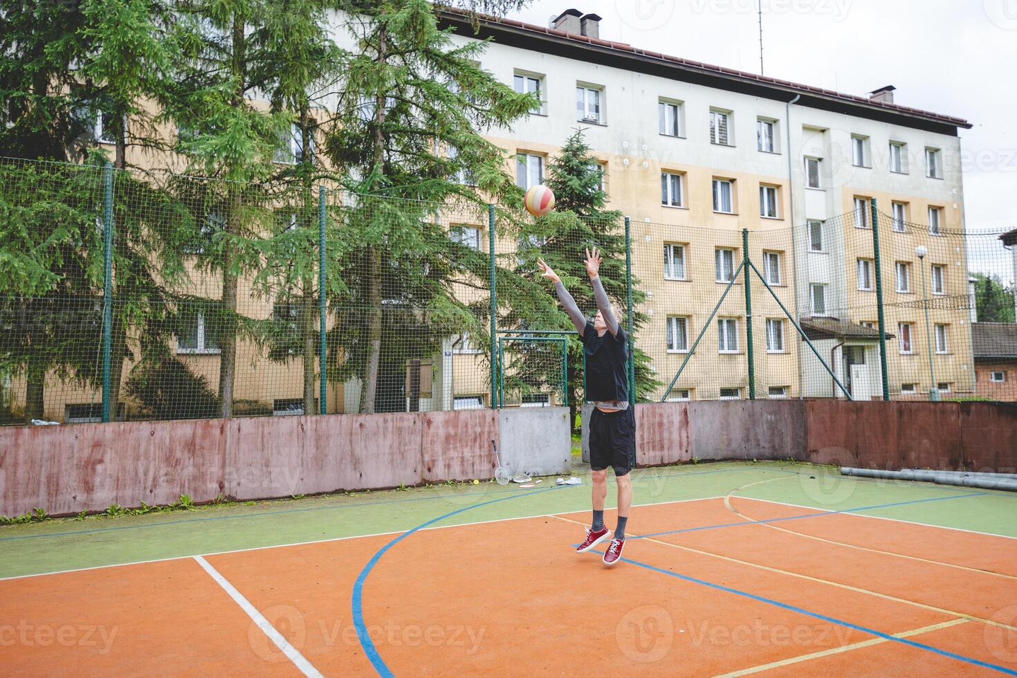 Volleyball player practicing setting the ball on a hard court, focusing on control and precision during an outdoor training session. A calm, focused moment in the game photo