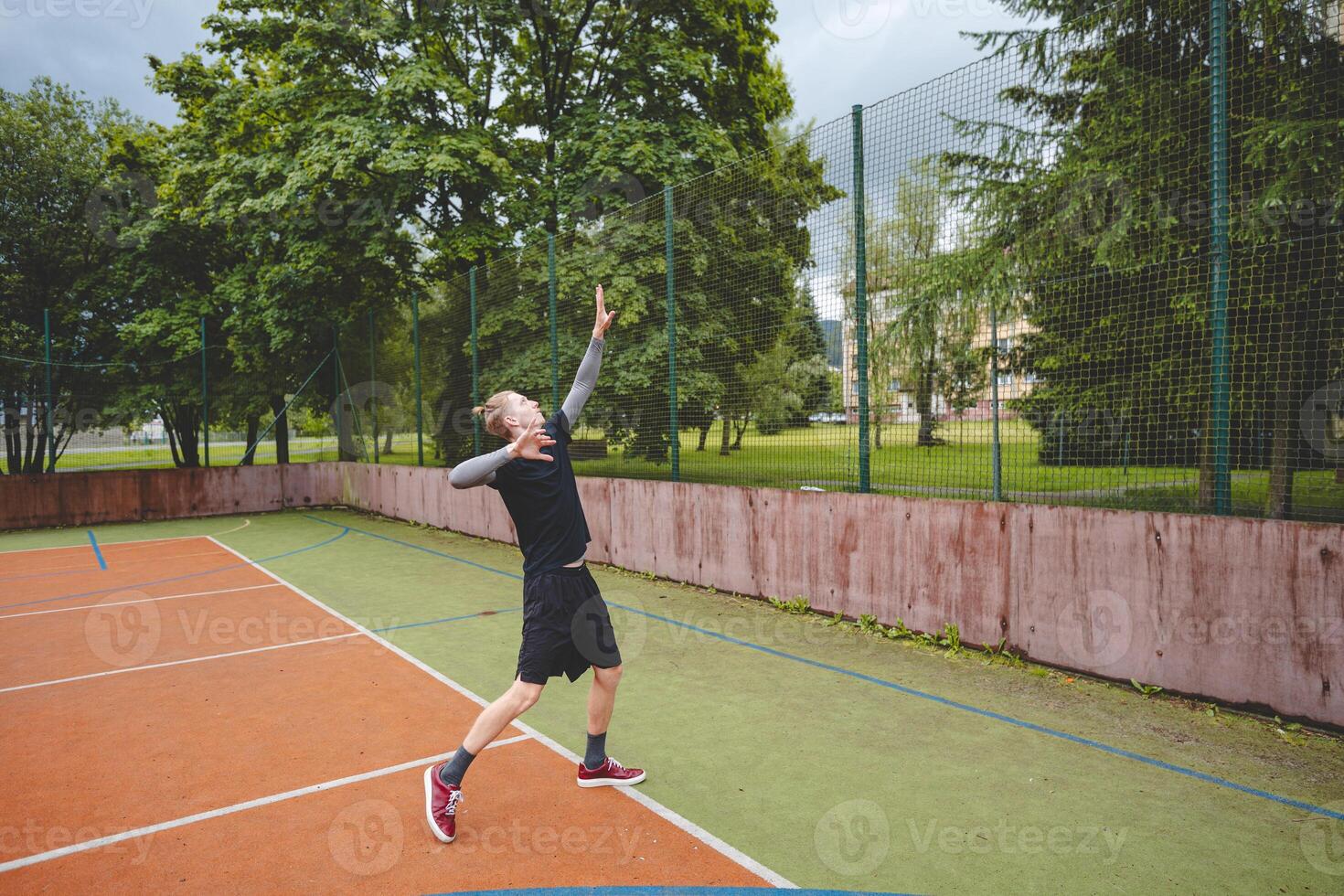 Volleyball player is serving on a hard court during an outdoor game. The action showcases athleticism, agility, and control in a dynamic volleyball setting photo