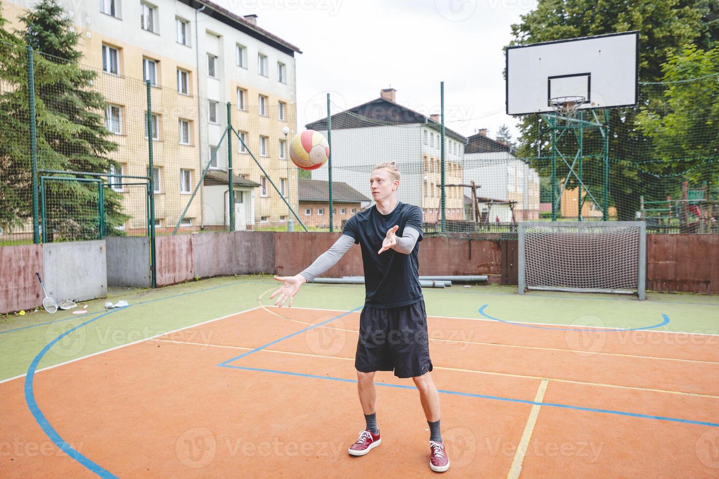 Volleyball player standing on a hard court, bouncing the ball while preparing for the next play during an outdoor game. A calm, focused moment before the action begins photo