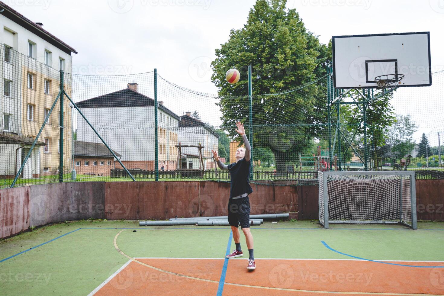 Volleyball player is serving on a hard court during an outdoor game. The action showcases athleticism, agility, and control in a dynamic volleyball setting photo