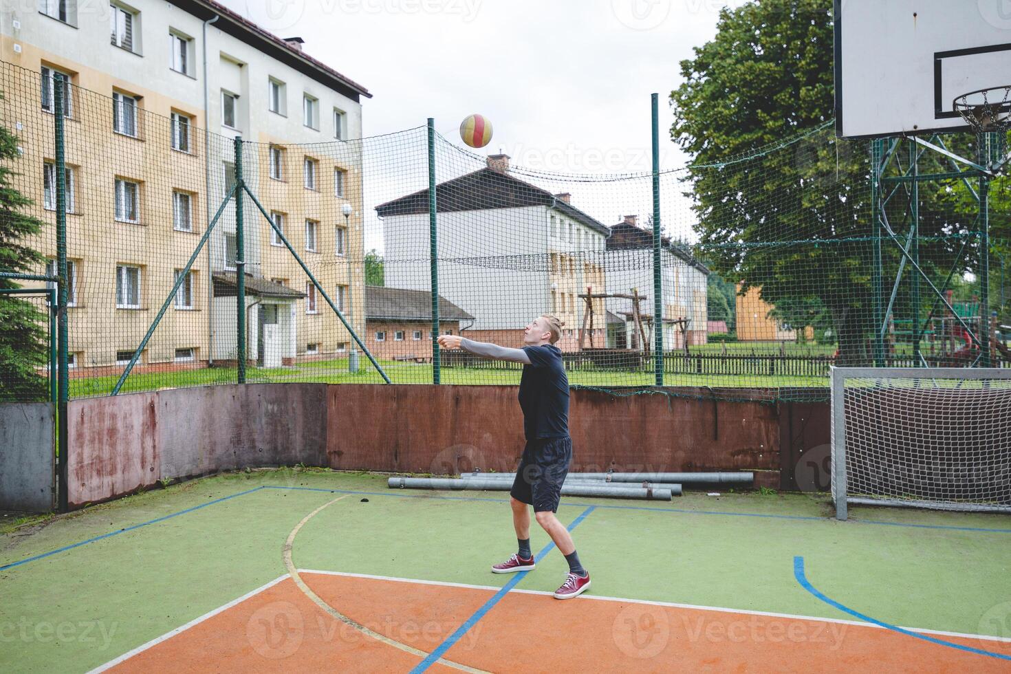 Volleyball player is passing on a hard court during an outdoor practice session. The action captures focus, movement, and ball control in a casual game setting photo