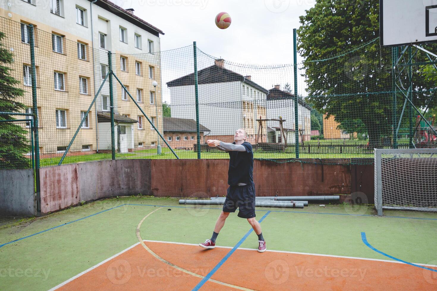 Volleyball player is passing on a hard court during an outdoor practice session. The action captures focus, movement, and ball control in a casual game setting photo