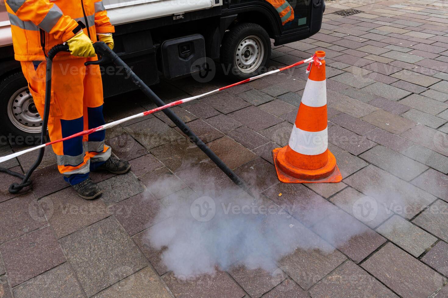 Road worker cleans the pavement with a steam pressure hose. photo