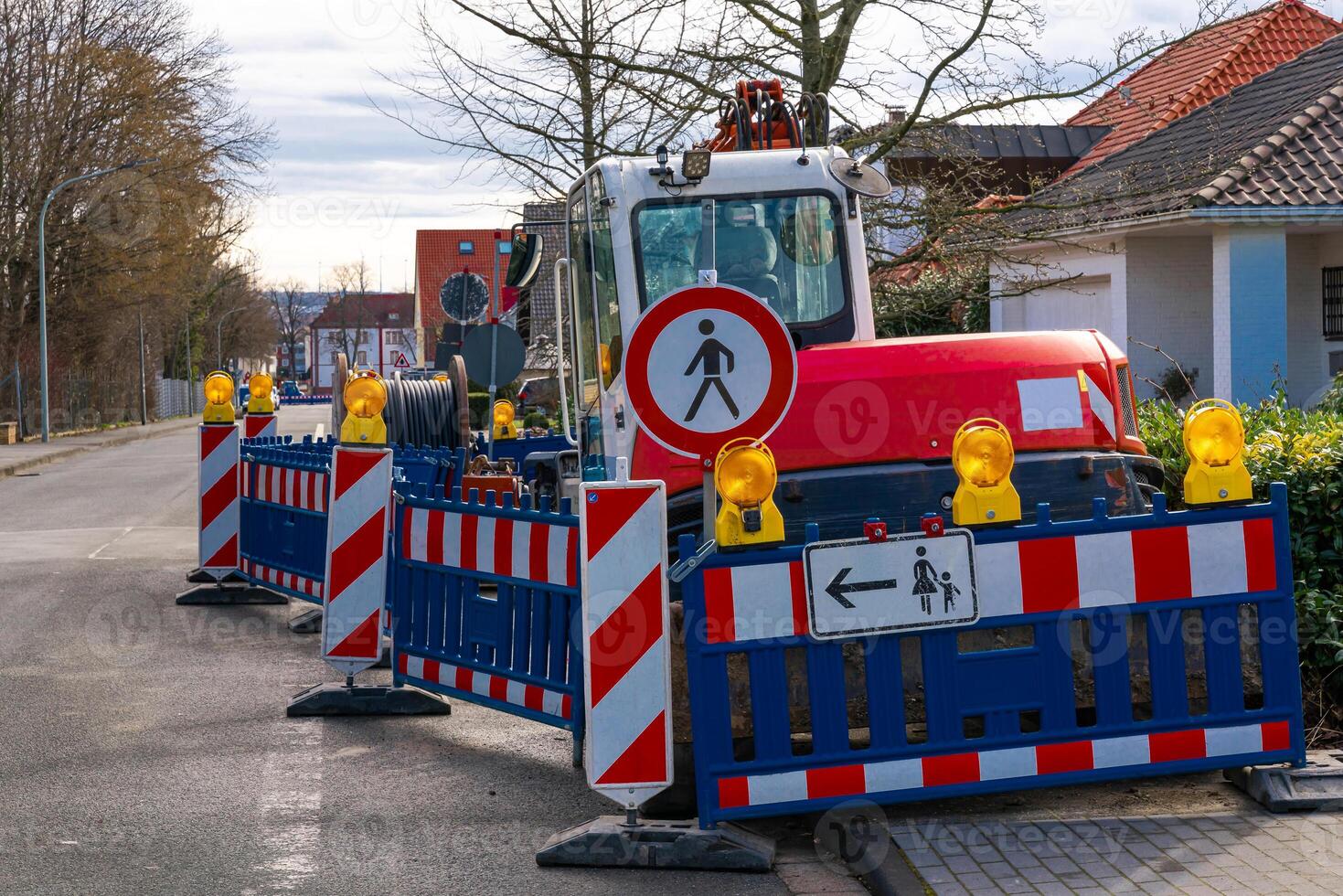 A small tractor standing on the sidewalk behind the barriers. Cabling. photo