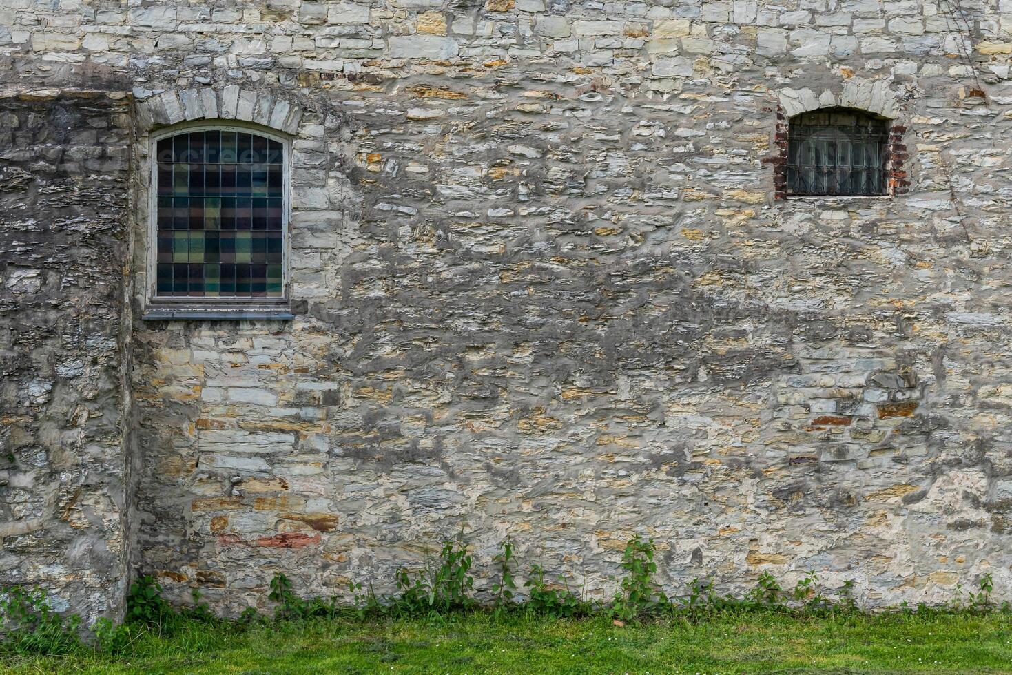 Fragment of a gray stone wall with arched windows. photo