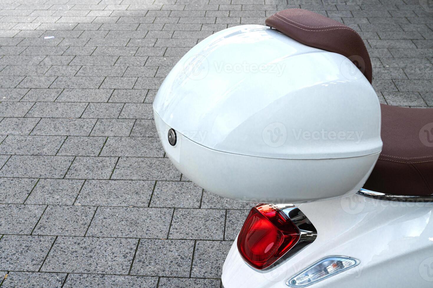 Part of a moped with a white plastic trunk and brake light. photo