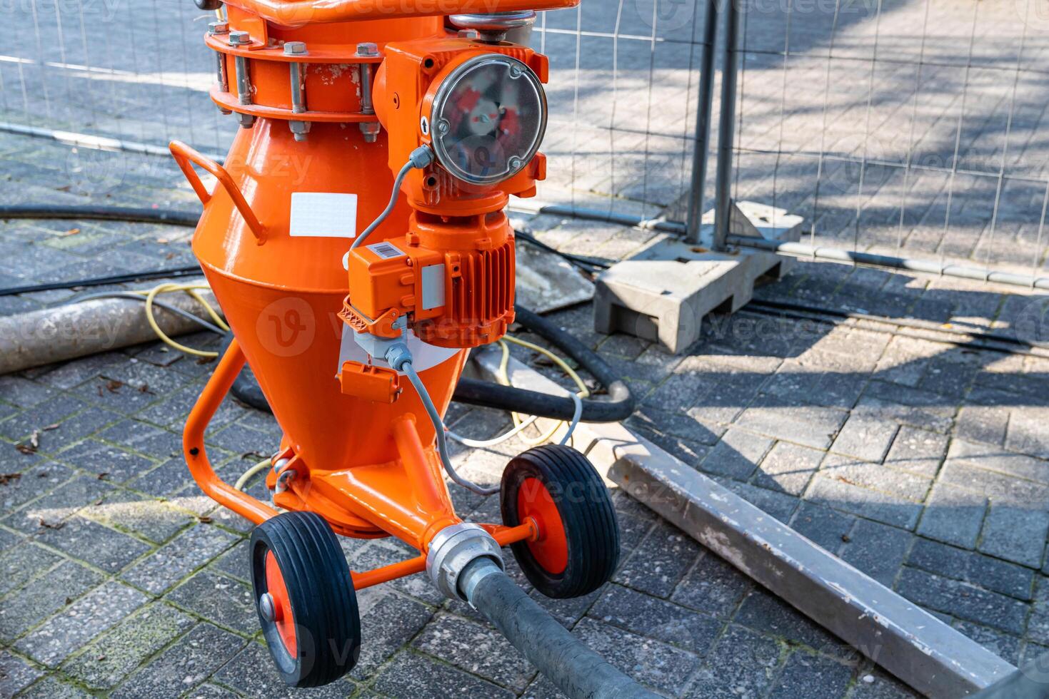 Part of orange mortar mixer with motor and supply hoses. photo