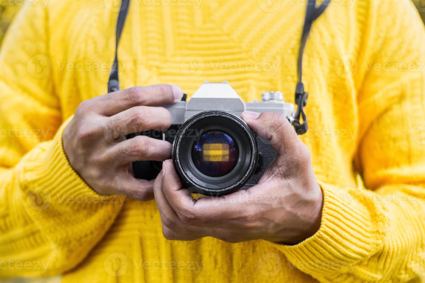 Hands of a man with yellow sweater holding a analog camera. photography vintage concept. photo