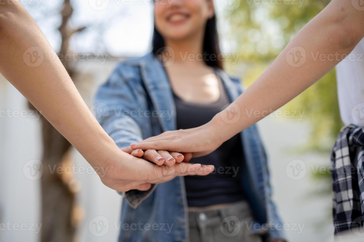 A close-up of college students putting their hands together while standing in their college park. photo