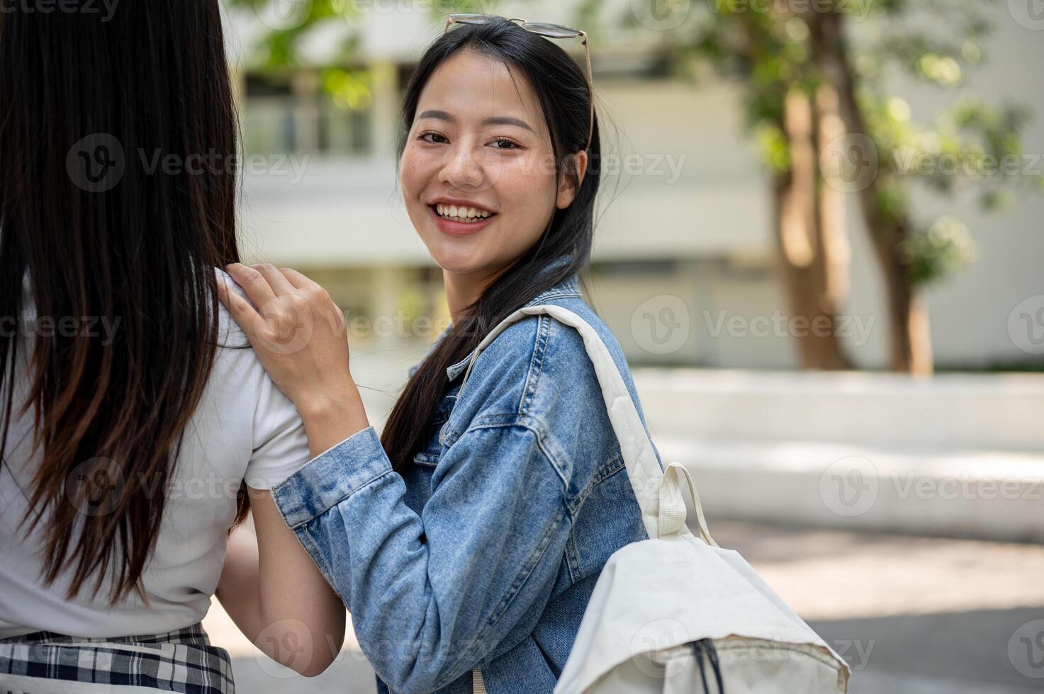 A happy Asian female college student is on the way to class with her friends, smiling at the camera. photo