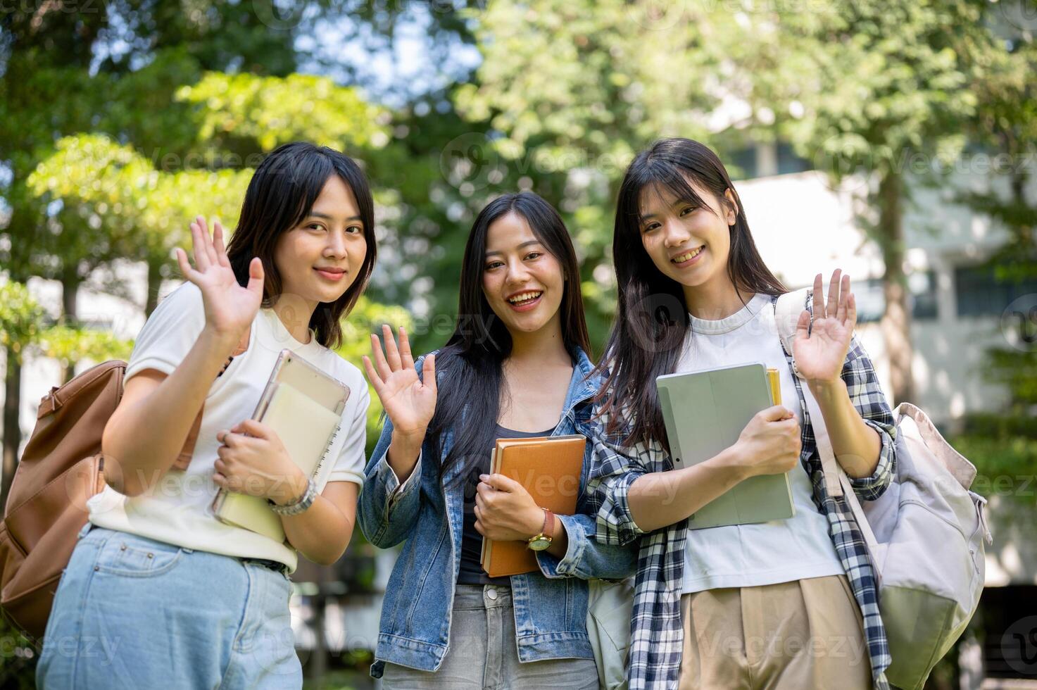 Portrait of charming and friendly Asian female college students waving and smiling at the camera. photo