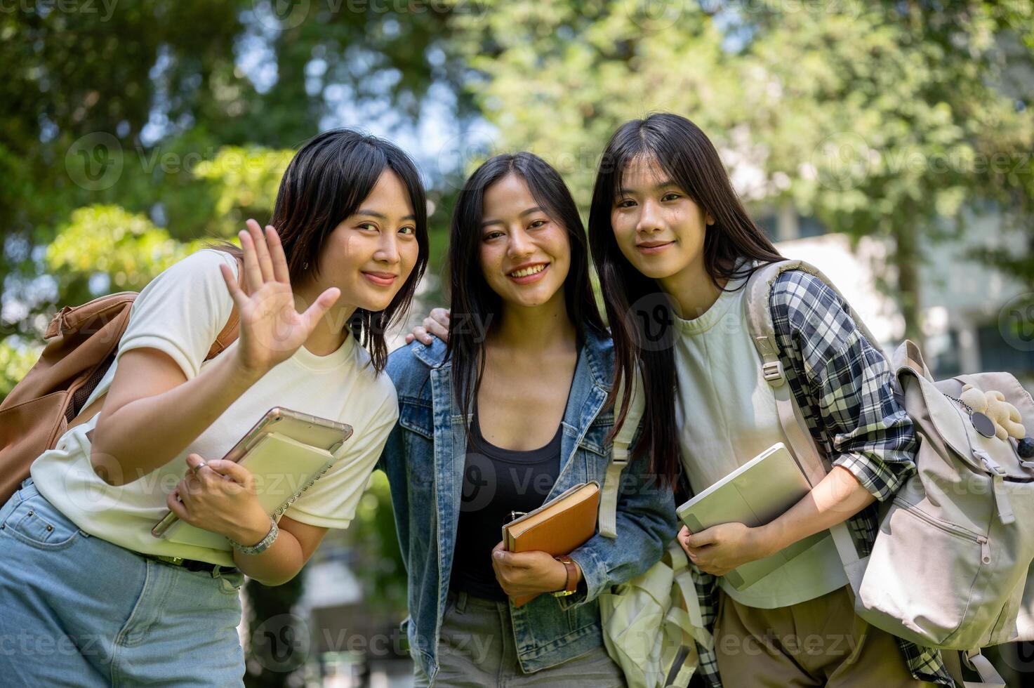 Portrait of charming and friendly Asian female college students waving and smiling at the camera. photo
