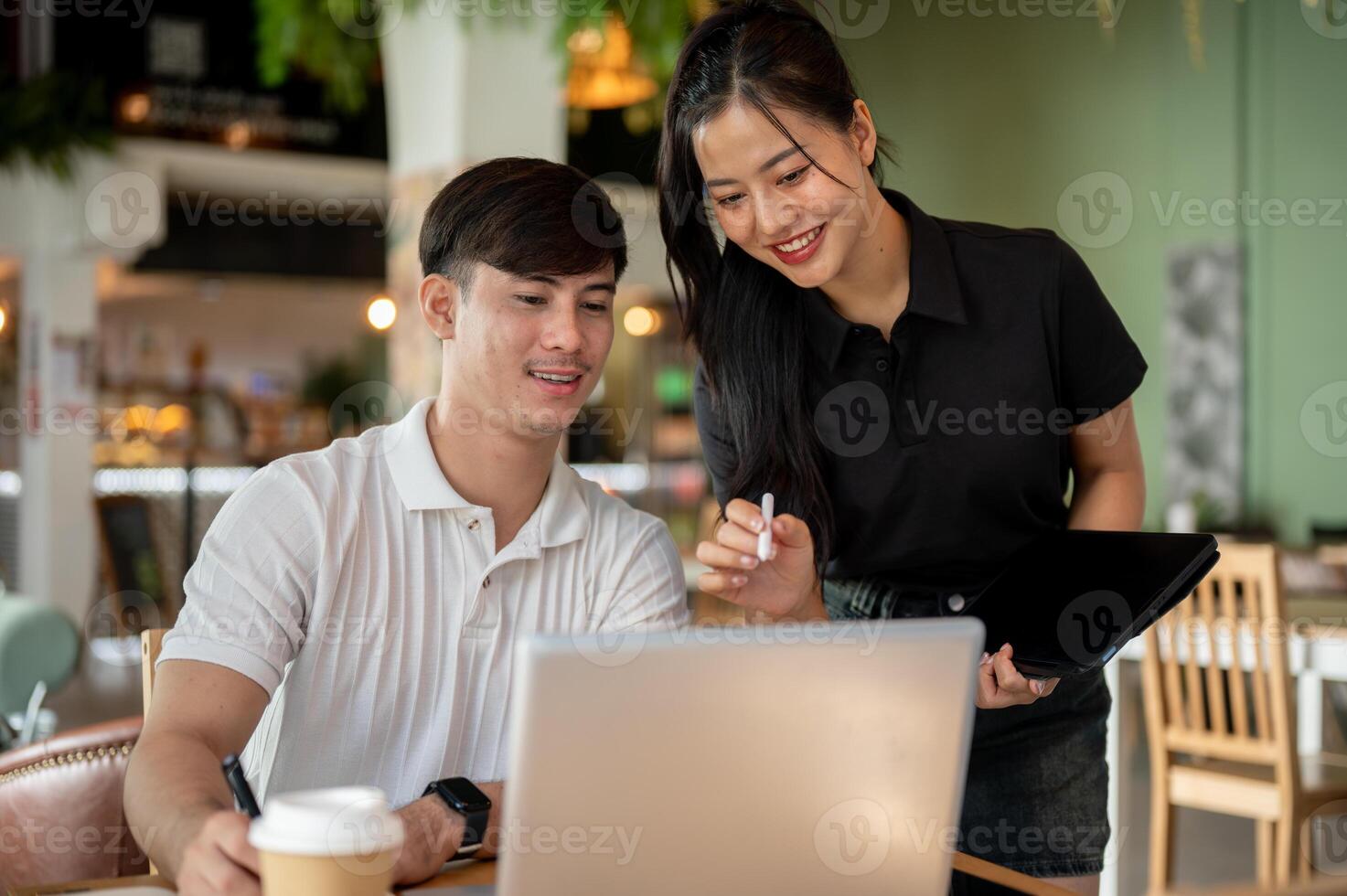 Two positive Asian colleagues are brainstorming together and discussing work. photo