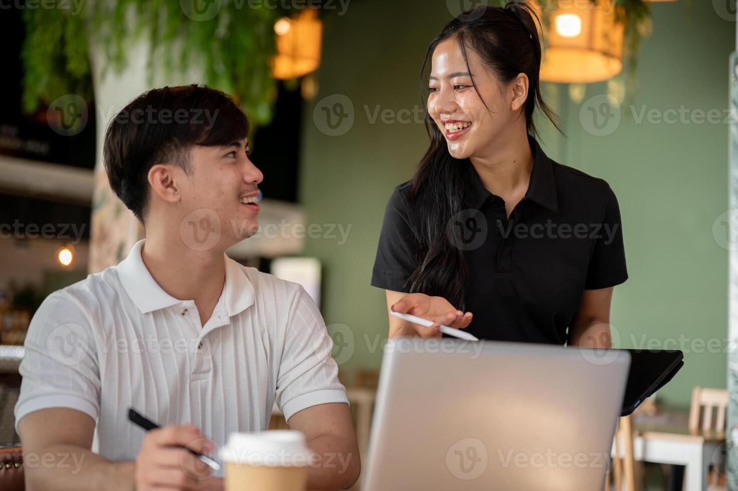 Two positive Asian colleagues are brainstorming together and discussing work. photo