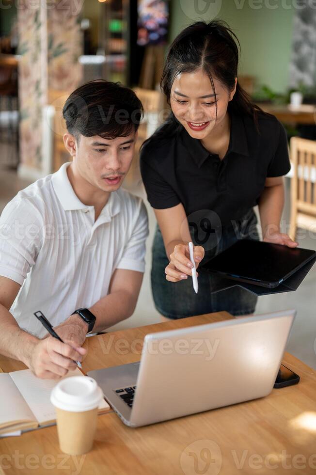 Two positive Asian colleagues are brainstorming together and discussing work. photo