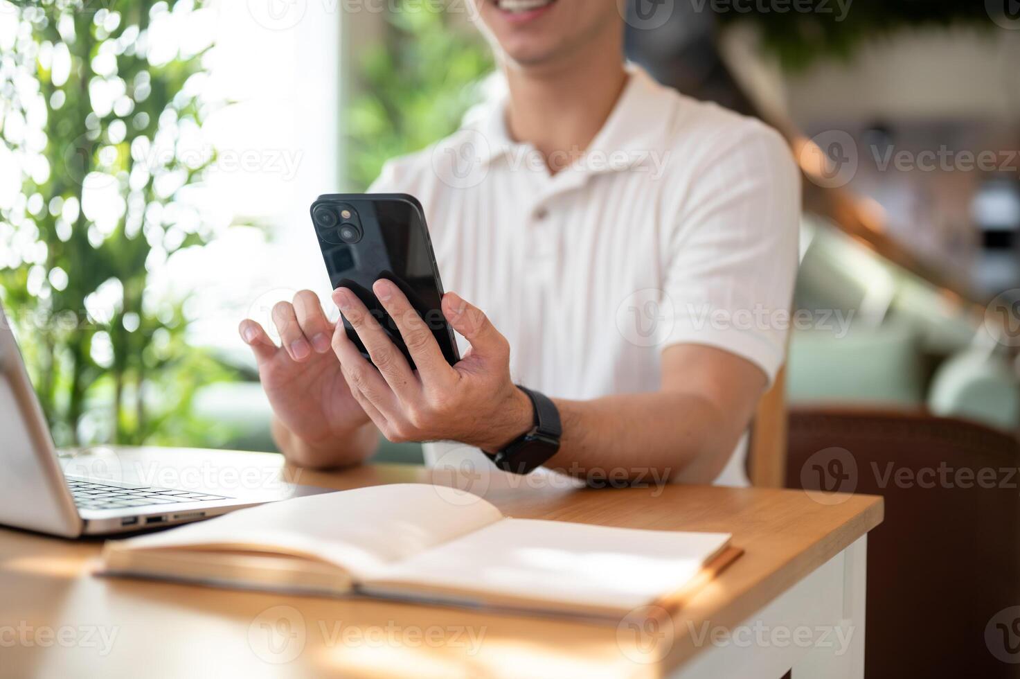 A man is reading chat messages on his smartphone while working remotely from a coffee shop. photo