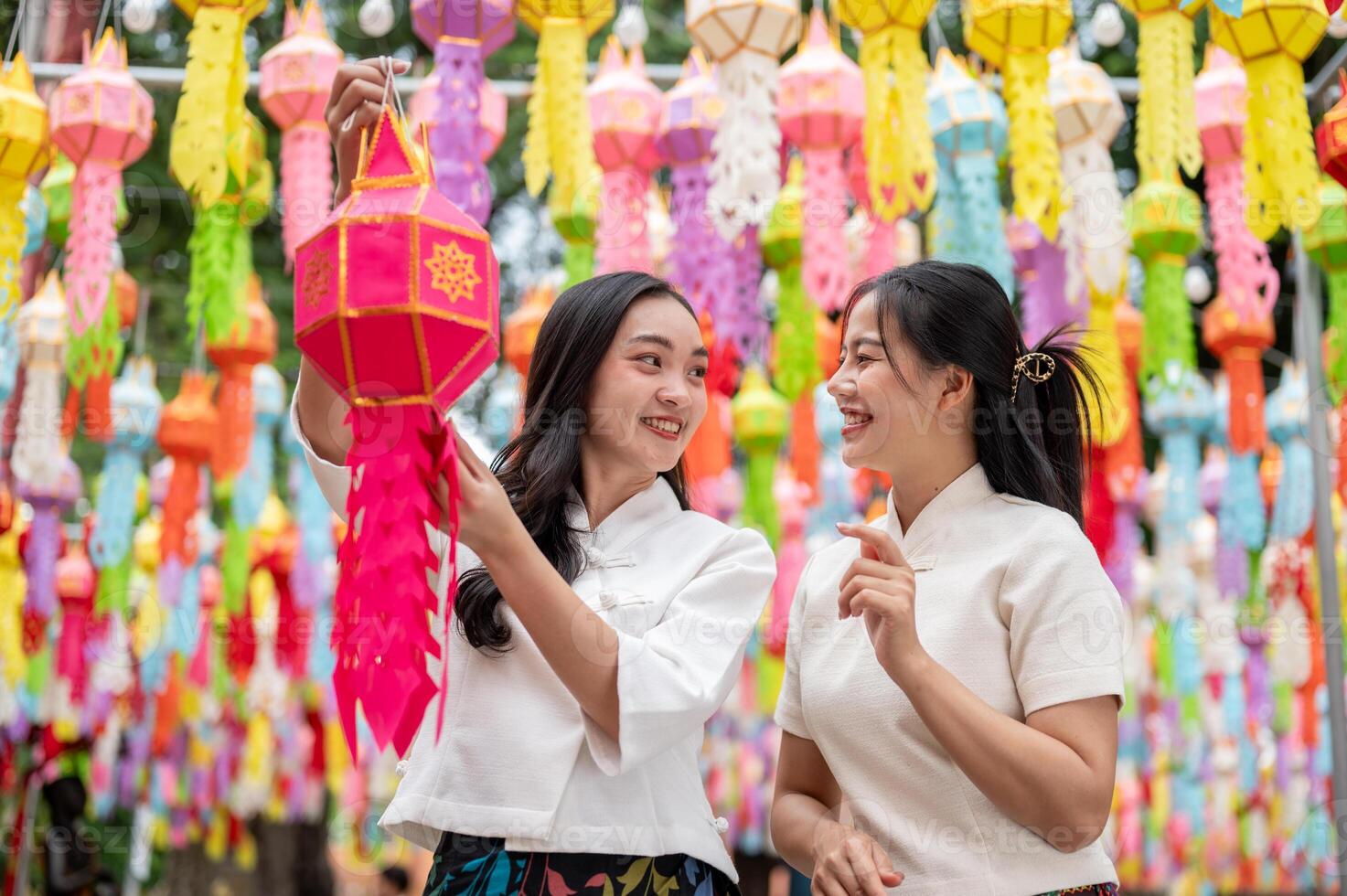 Two beautiful Asian women in traditional dresses enjoy a traditional lantern festival at a temple. photo