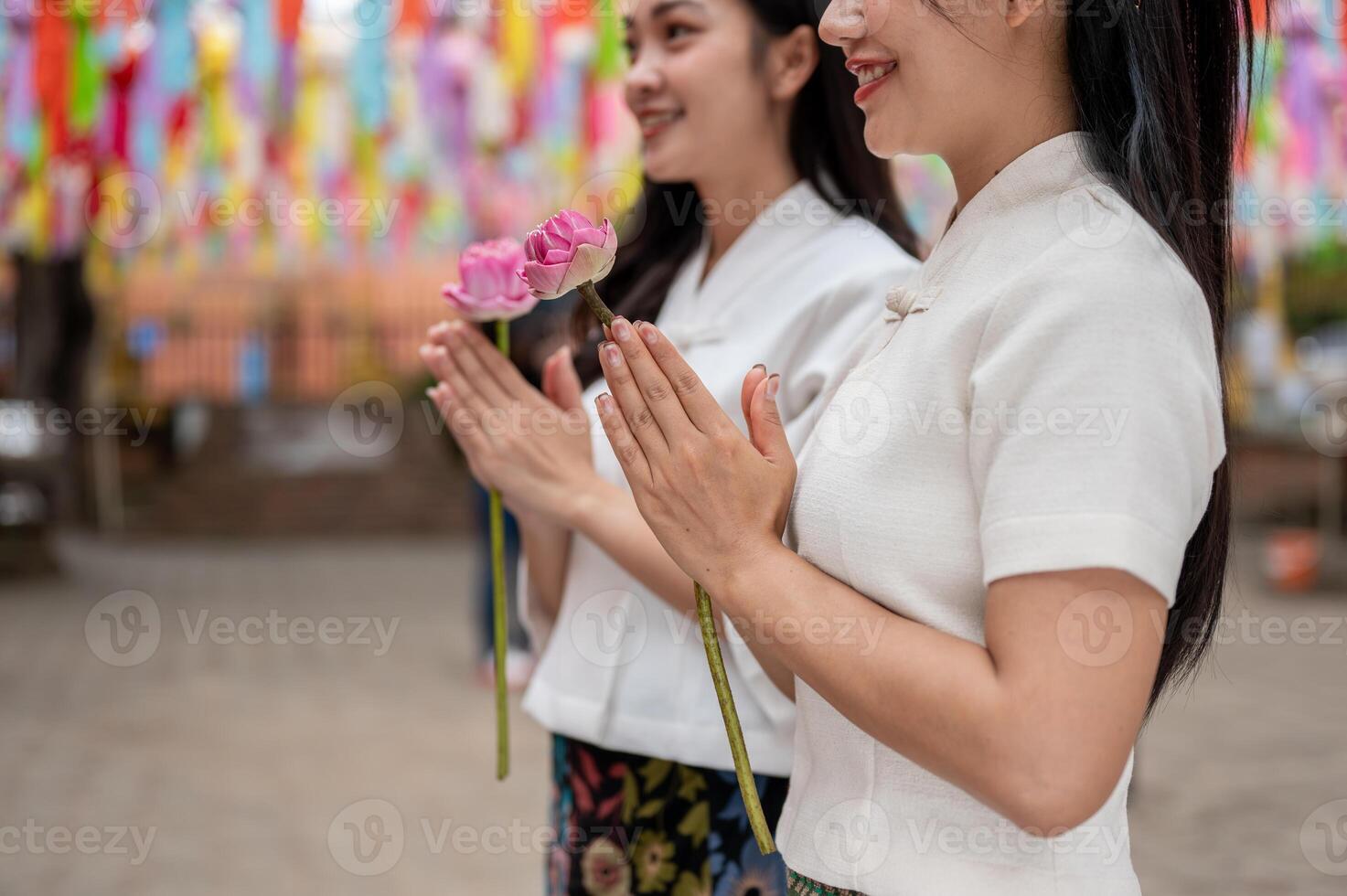 A close-up of two beautiful Asian women praying at a temple during a traditional festival. photo