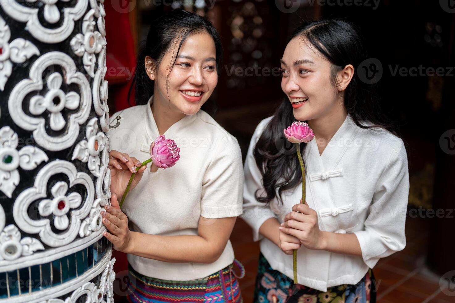 Beautiful Asian women in traditional dresses enjoy a conversation while standing in a temple. photo