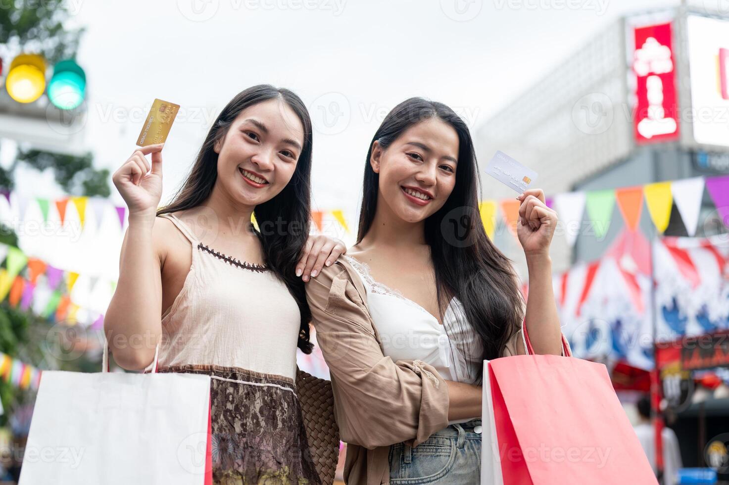 Beautiful Asian women showing their credit card to the camera while standing in a city market. photo