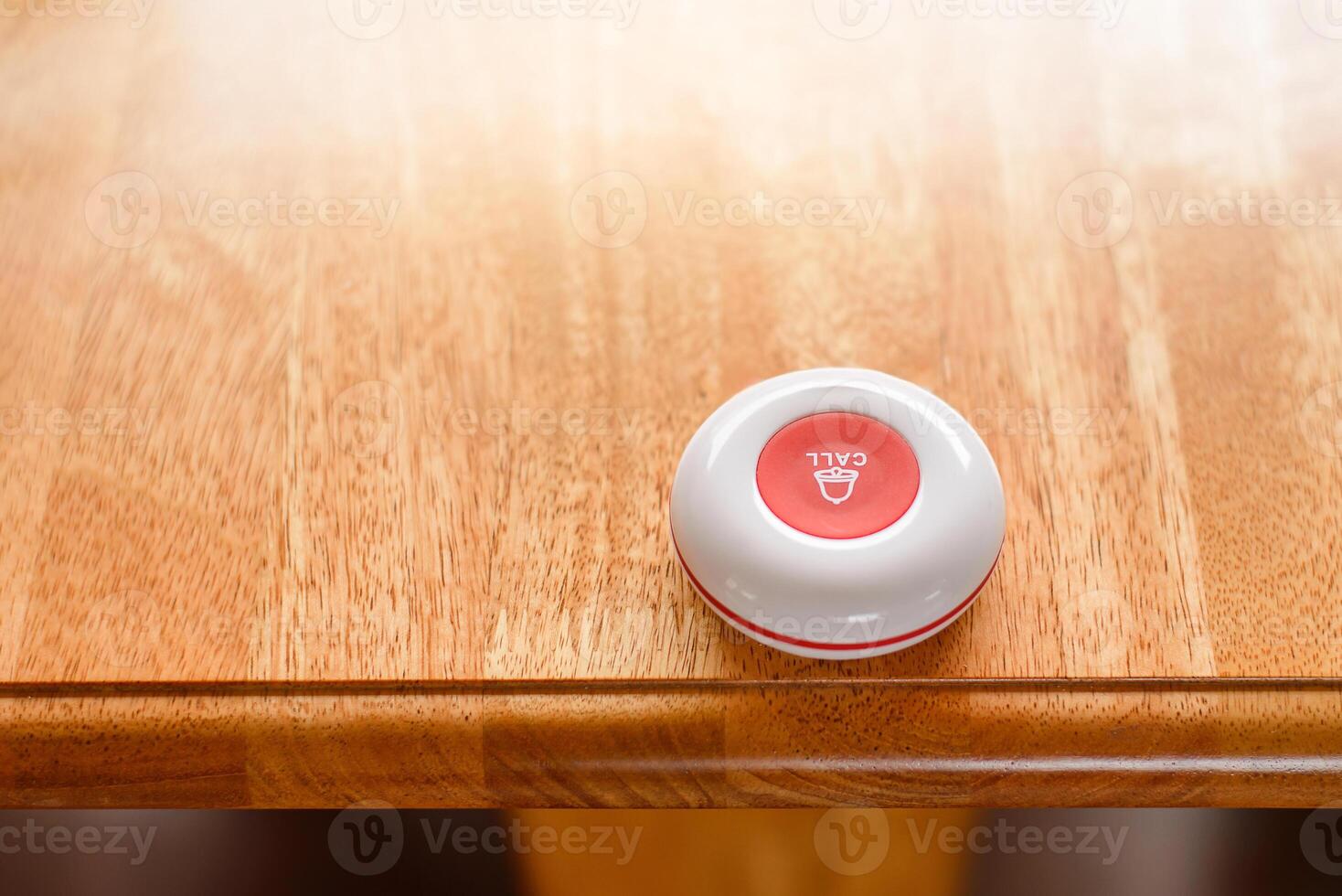 A white call button on a wooden table photo