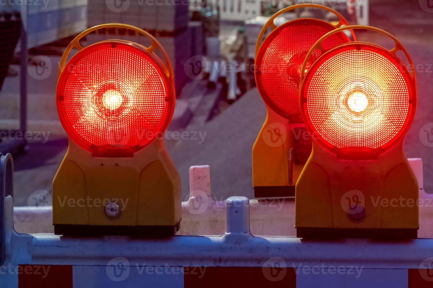 Red warning lights flashing on construction site barrier at dusk photo