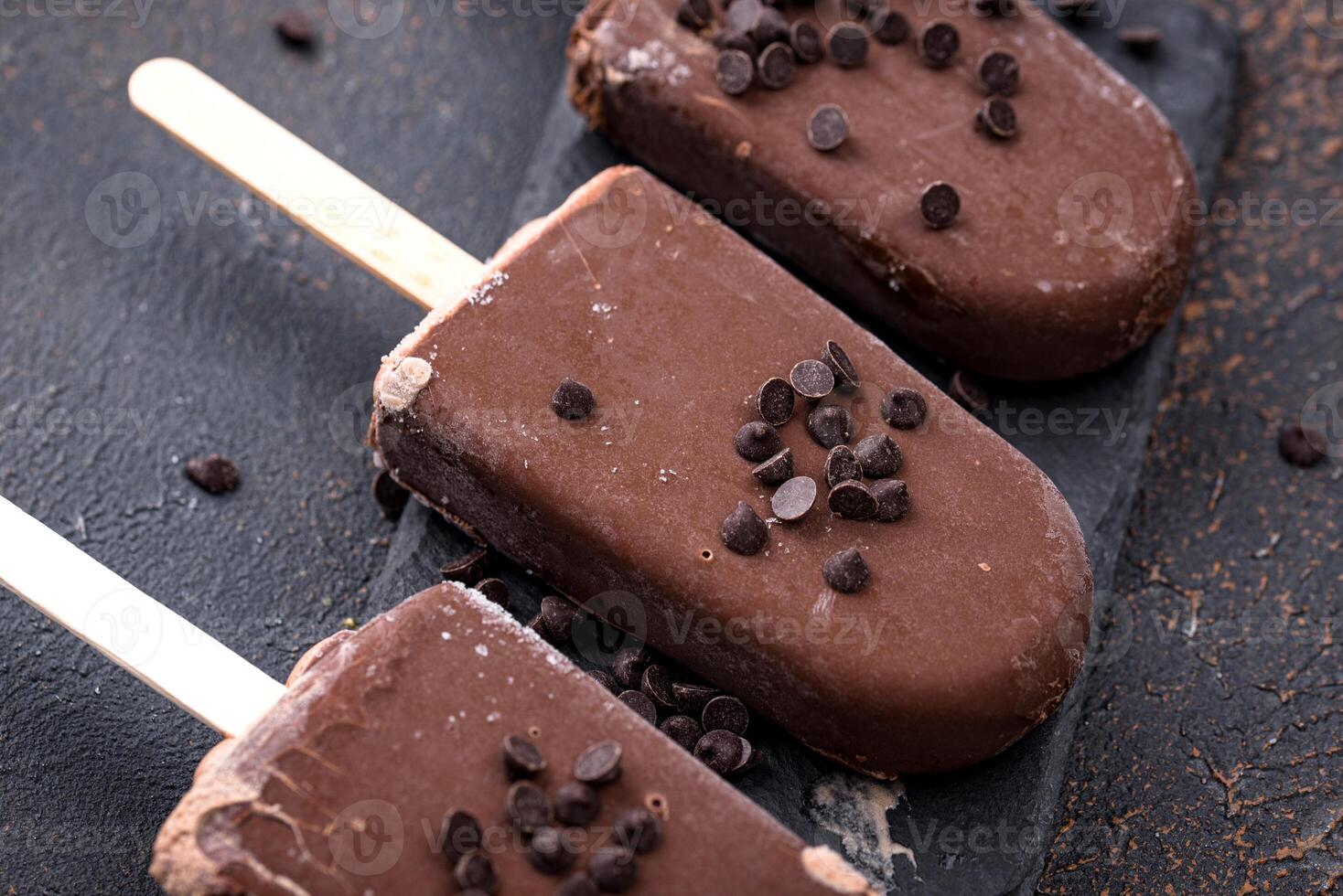 Delicious chocolate popsicles on dark background photo