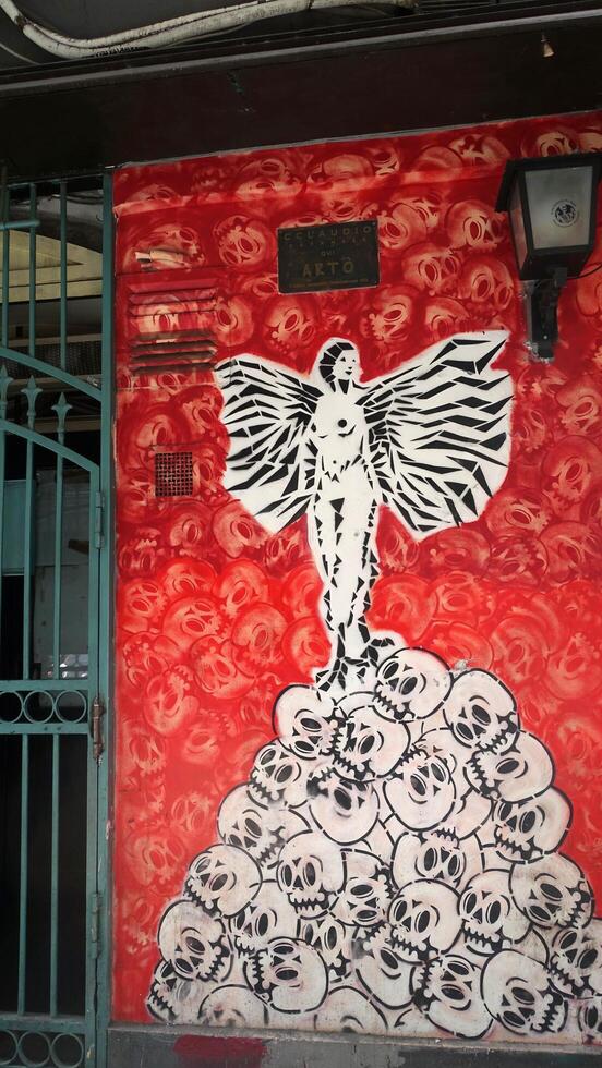 Naples, Italy. June 23, 2024. An angel on a pile of skulls depicted on a wall in the historic center. photo