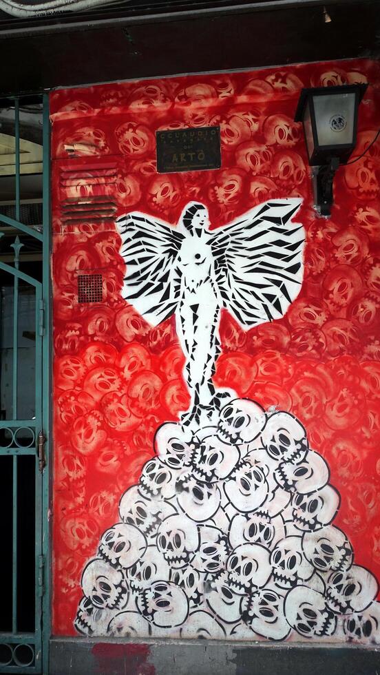 Naples, Italy. June 23, 2024. An angel on a pile of skulls depicted on a wall in the historic center. photo
