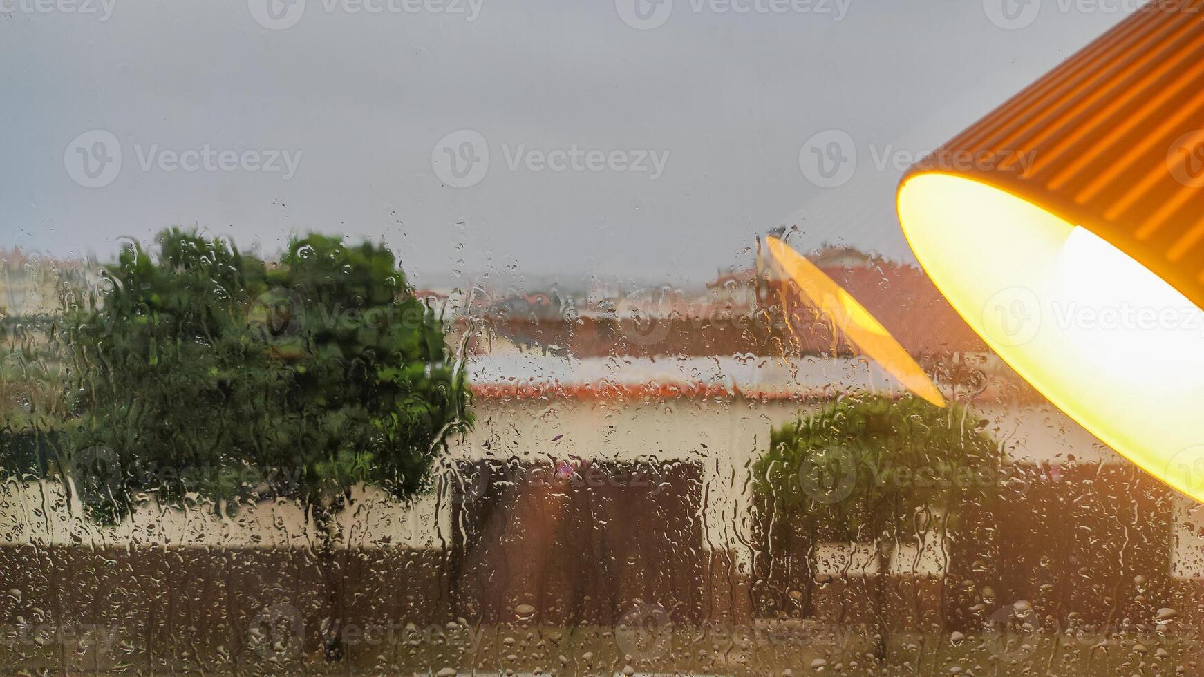 Rainy window view with warm interior lamp reflection in foreground photo