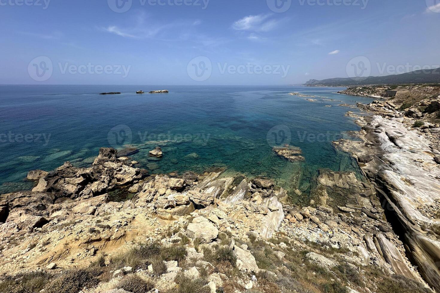 The breathtaking shoreline reveals a mix of rugged rocks and serene turquoise waters, showcasing the tranquil beauty of nature along the coastline under a clear sky photo