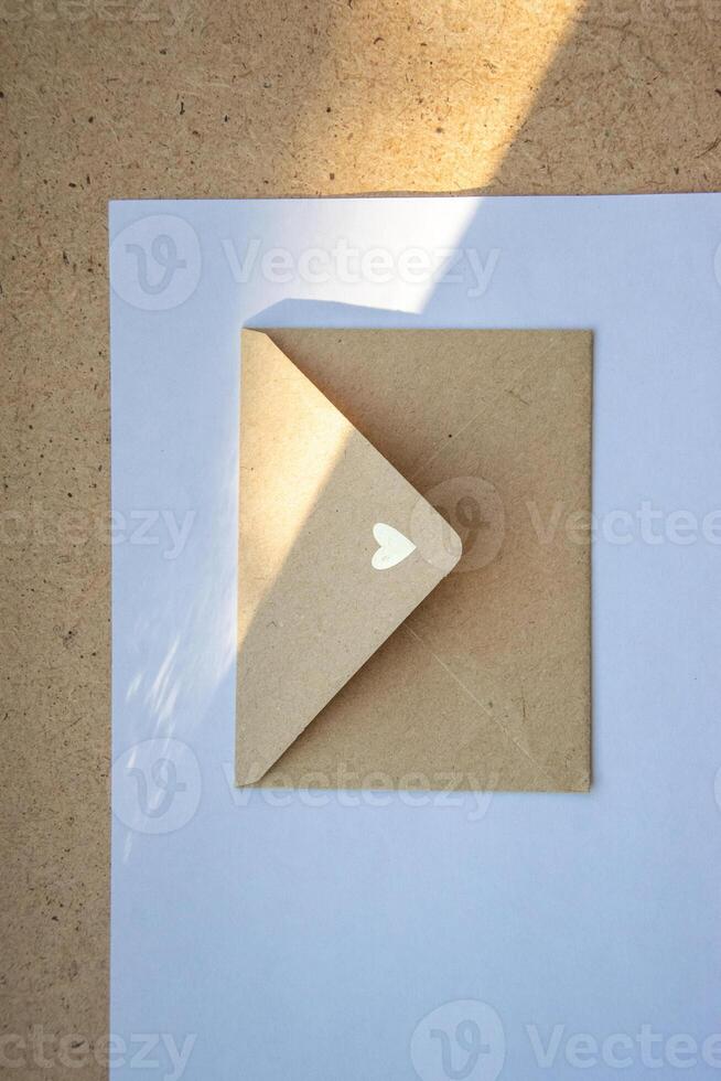 A delicate envelope with a heart design partially opened on a light surface during daylight photo