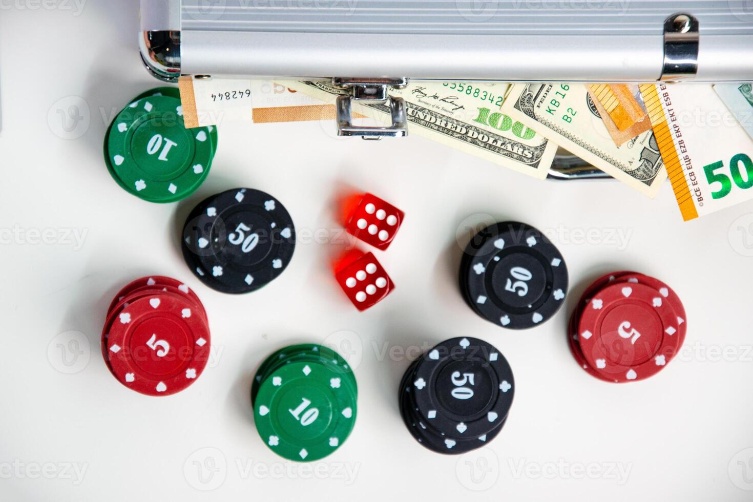 A close-up shot of a table with poker chips, dice, and a silver case full of cash photo