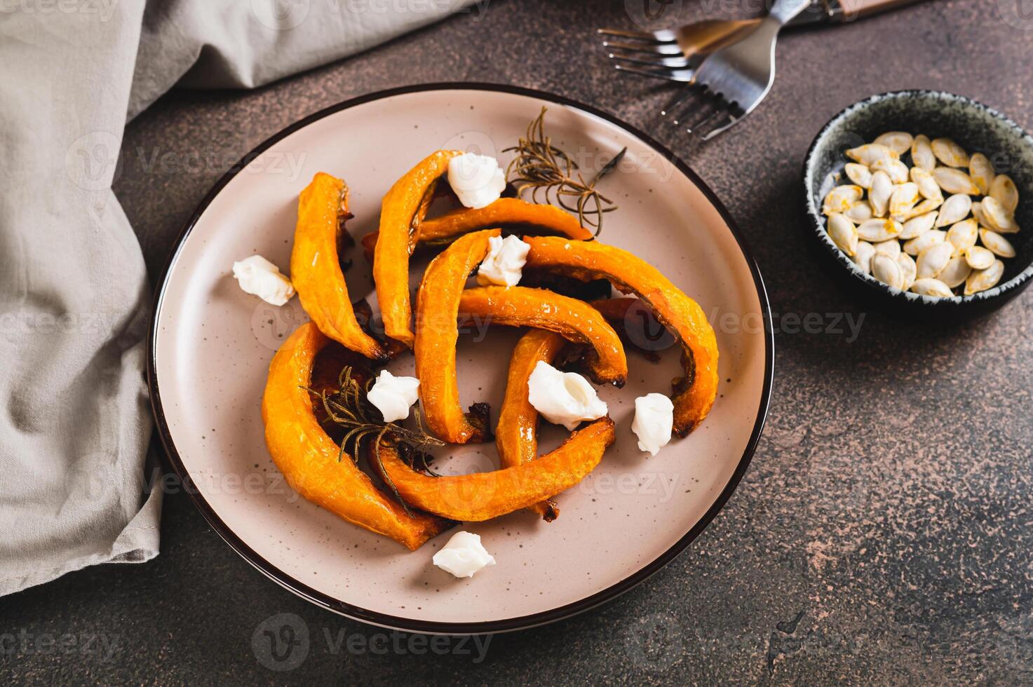 Appetizing pieces of sweet pumpkin baked with rosemary on a plate on the table photo